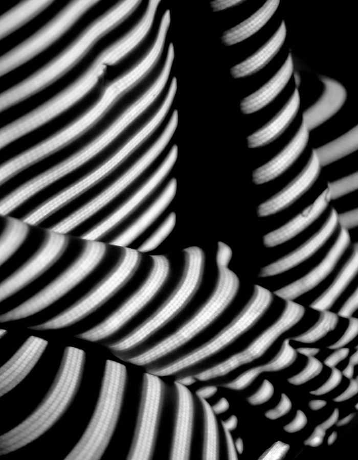 Abstract black and white image focusing on striped shadows creating depth and intrigue.